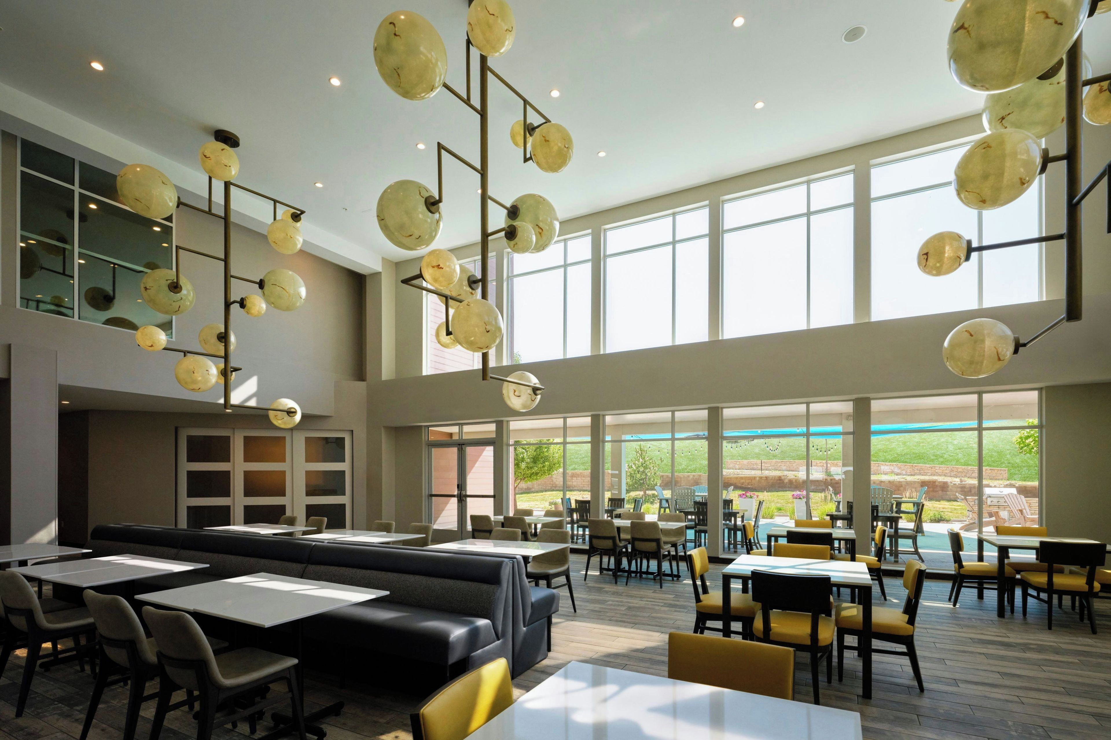 A spacious indoor area with multiple seating options, including tables and booths, and large windows providing a view of the outdoors.