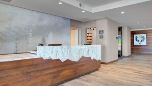 A reception area with a marble counter, wooden paneling, and a tiled floor. - Fairfield by Marriott Inn & Suites Boulder Broomfield/Interlocken (Broomfield)