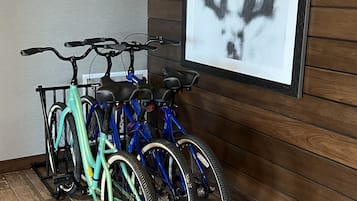 Une pièce avec un plancher en bois, un cadre photo accroché au mur et un porte-vélos contenant deux bicyclettes.