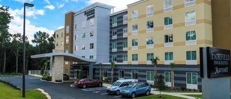 Ein Hotel Fairfield Inn & Suites by Marriott mit modernem Design, mehreren Etagen und einem Parkplatz mit einigen Autos.
