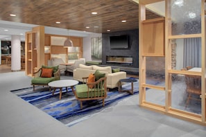 A modern living room with a fireplace, wooden furniture, and a large TV.