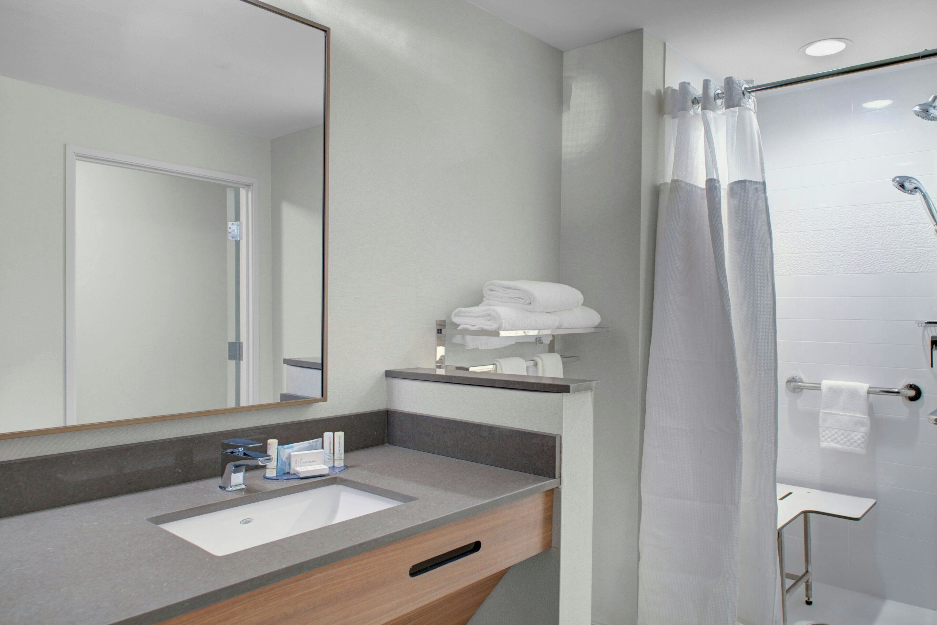 Un baño moderno con lavamanos, espejo y zona de ducha.