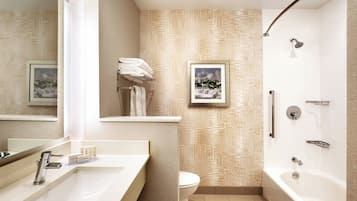 A modern bathroom with a large mirror, a sink, a toilet, and a bathtub.
