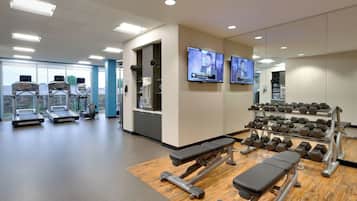 A gym with treadmills, a bench press, and dumbbells.