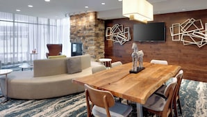 Un salon moderne avec une table à manger en bois, des sièges confortables, un mur décoratif en pierre et une grande fenêtre.