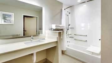 Une salle de bain moderne avec un grand miroir, deux lavabos, une baignoire et une douche.