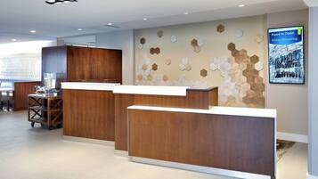 Un área de recepción con un mostrador de madera, una pantalla digital en la pared y un adorno hexagonal.