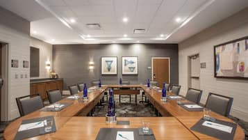 Une salle de conférence avec une longue table, des chaises et un pupitre.