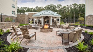 A patio area with a fire pit, outdoor furniture, and a covered seating area. - Homewood Suites by Hilton Saratoga Springs (Saratoga Springs)