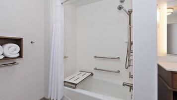 A modern bathroom with a walk-in shower, grab bars, and a towel rack.