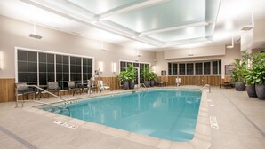 An indoor swimming pool with clear lane markings, lounge chairs, and potted plants. - Homewood Suites by Hilton Saratoga Springs (Saratoga Springs)