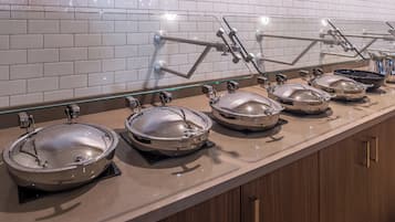 A buffet setup with multiple serving stations, each with a covered bowl and a glass display case.