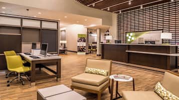 A hotel lobby with a reception desk, seating area, and a dining space.