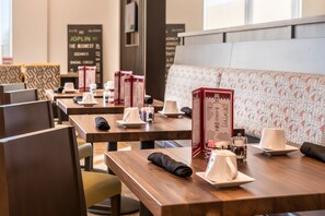 Un restaurant avec des tables en bois, des serviettes blanches et des panneaux affichant le menu.