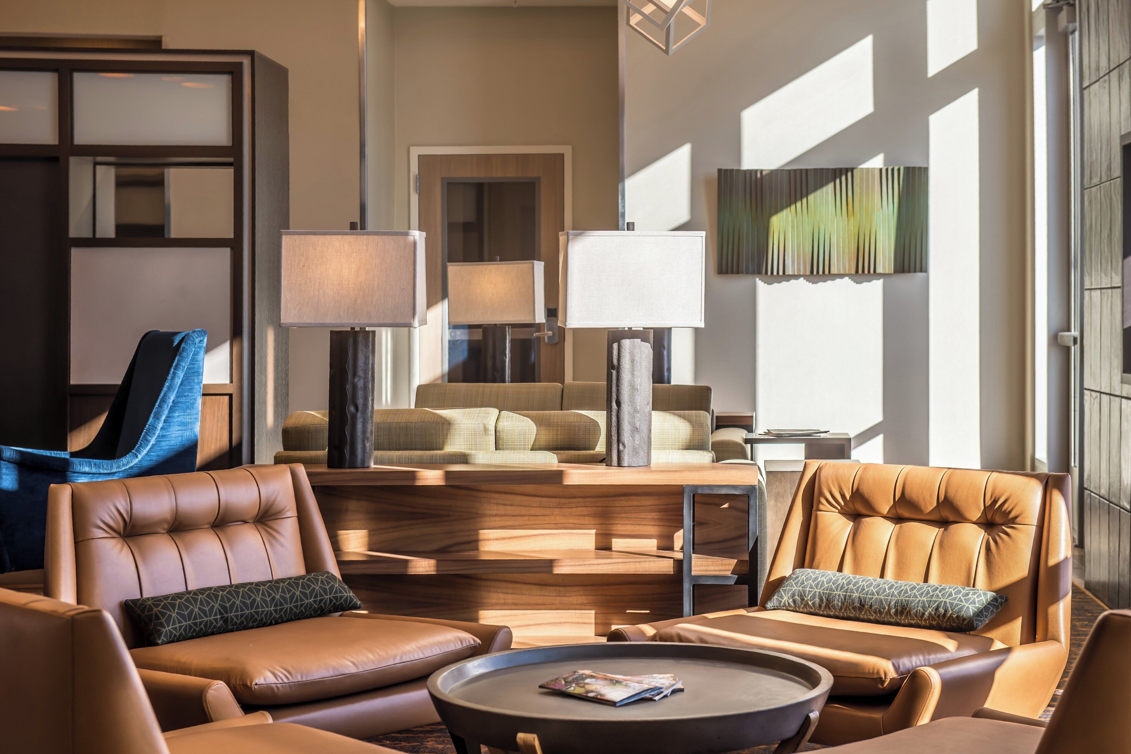 A modern living room with leather sofas, a coffee table, and a large window providing natural light.