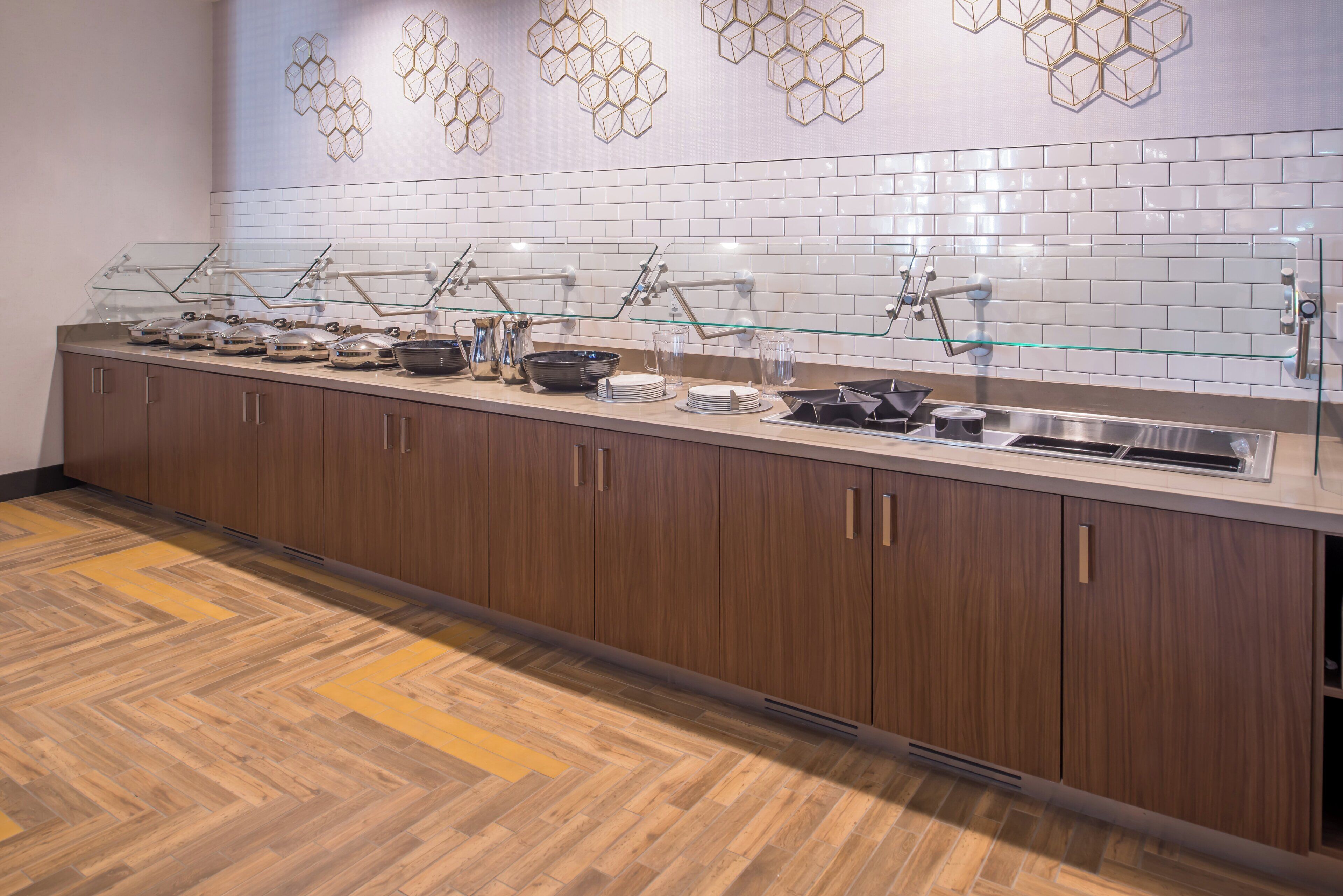 Una cocina moderna con una encimera larga, electrodomésticos de acero inoxidable y un adorno hexagonal en la pared.