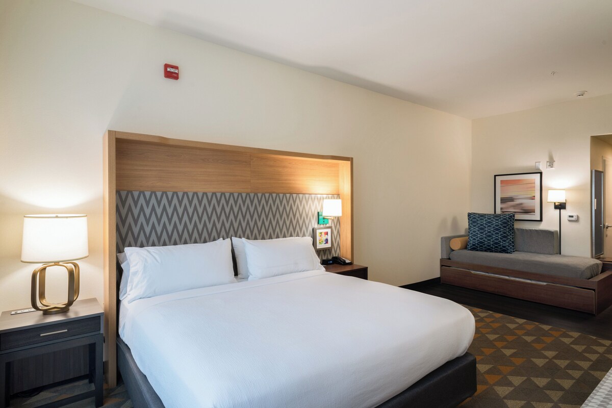 Une chambre d’hôtel comprenant un lit, des tables de chevet, une commode, un bureau et un canapé.