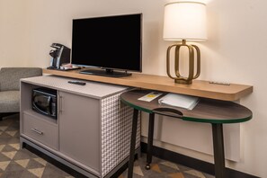 Une chambre d’hôtel compacte comprenant un coin cuisine, un téléviseur à écran plat, une lampe et une petite table.