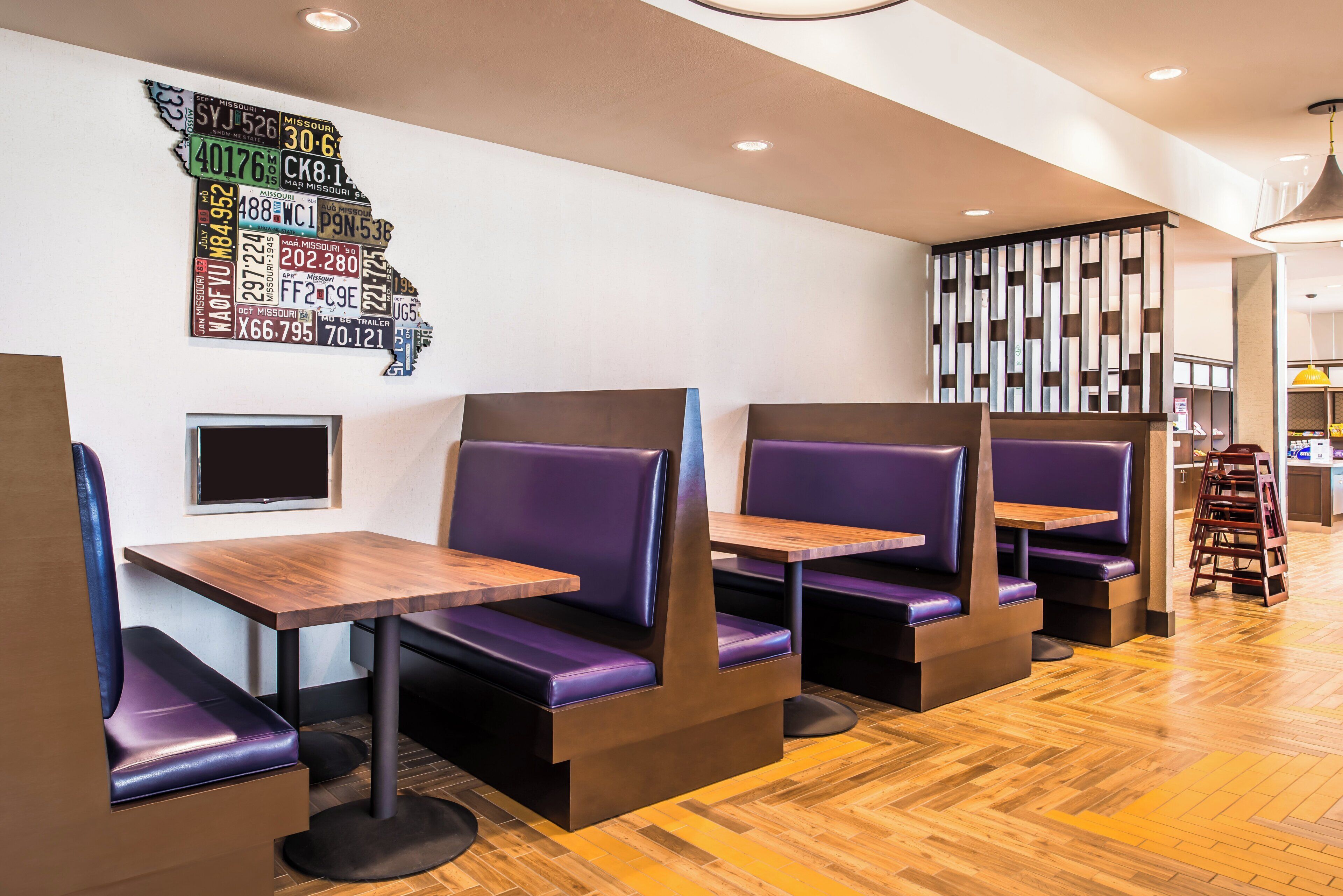 A restaurant interior with booths, tables, and a wall decoration of license plates.