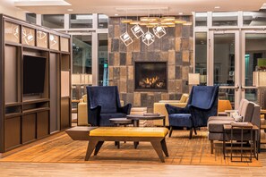 A modern lounge area with a fireplace, comfortable seating, and a television. - Holiday Inn Joplin by IHG (Joplin)