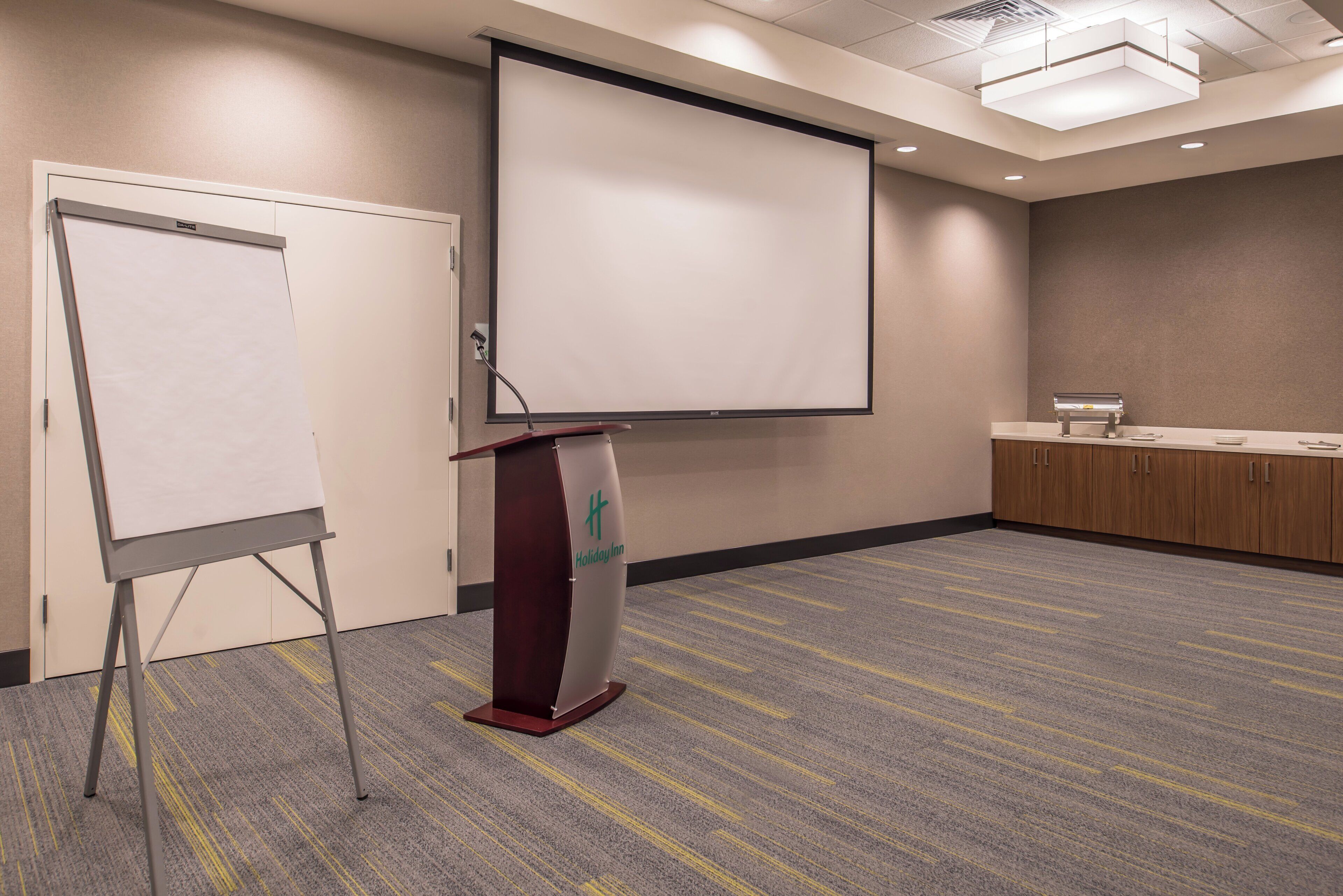 A conference room with a whiteboard, a projection screen, and a podium.
