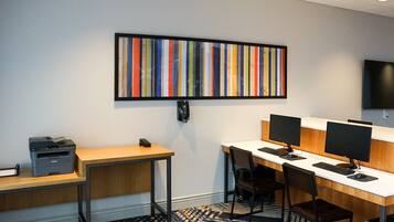 A modern office space with a desk, computer, printer, and a colorful abstract painting on the wall.