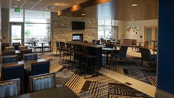 Un restaurante moderno con pared de piedra, televisor de pantalla plana y alfombra estampada.