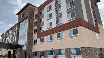 A multi-story hotel with a stone facade, large windows, and a parking lot.