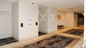 A hotel corridor with a patterned carpet, a bench, and a sign indicating a fitness center. - Holiday Inn Express & Suites Denver - Aurora Medical Campus by IHG (Aurora)