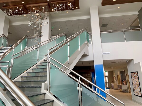 Un intérieur moderne avec un escalier en verre, des rampes en métal et un luminaire décoratif au plafond.
