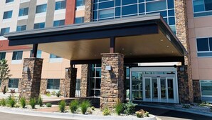 A Holiday Inn Express & Suites building with a stone facade, large windows, and a covered entrance. - Holiday Inn Express & Suites Denver - Aurora Medical Campus by IHG (Aurora)
