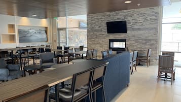 Un restaurante moderno con pared de piedra, televisor de pantalla plana y una variedad de opciones de asientos, incluyendo mesas y cabinas.