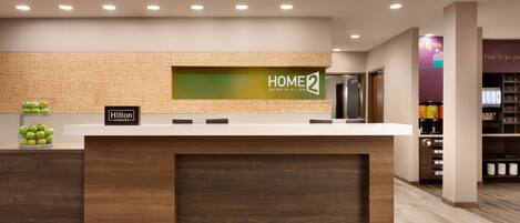 Un mostrador de recepción con un letrero que dice "HOME2 Suites by Hilton" y un letrero de "Hilton Honors".