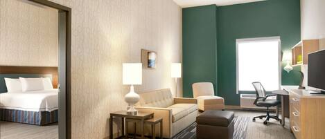 A hotel room with a bed, a sofa, a desk, and a chair.