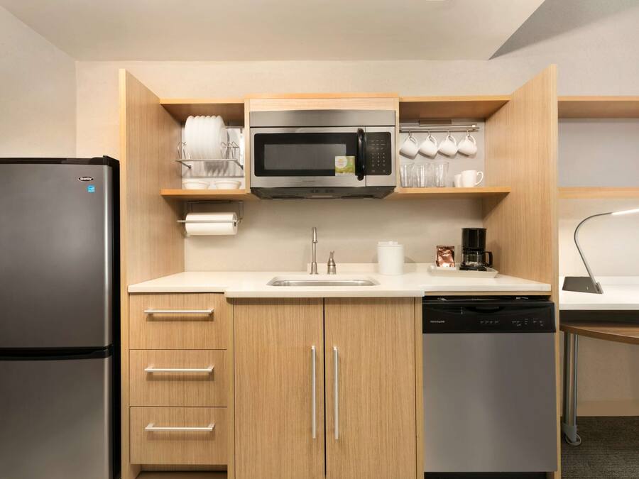A compact kitchen with a stainless steel refrigerator, a microwave, and a dishwasher.
