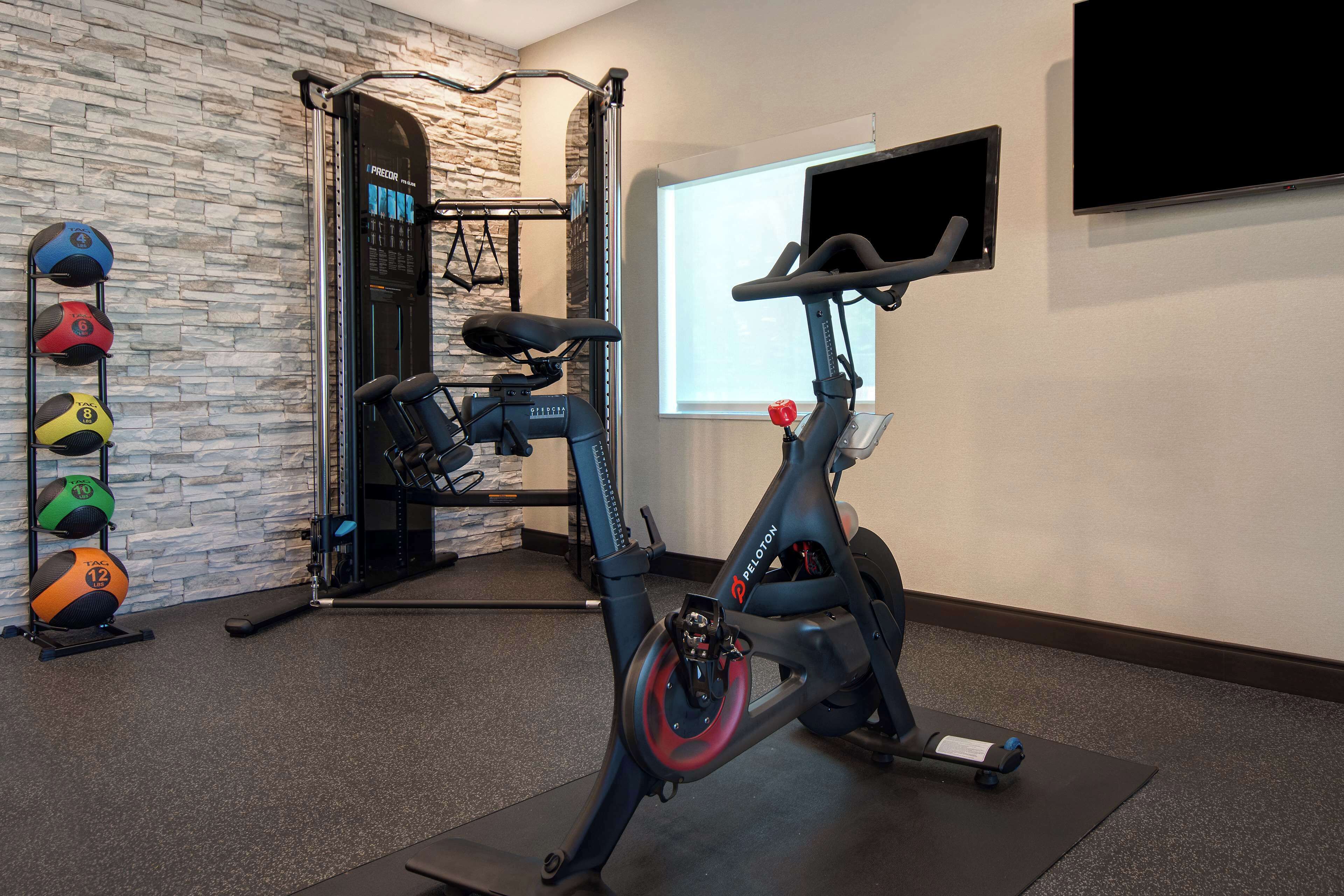 Et hjemmegymnasium med en motionscykel, en pull-up bar og et tv ophængt på væggen.