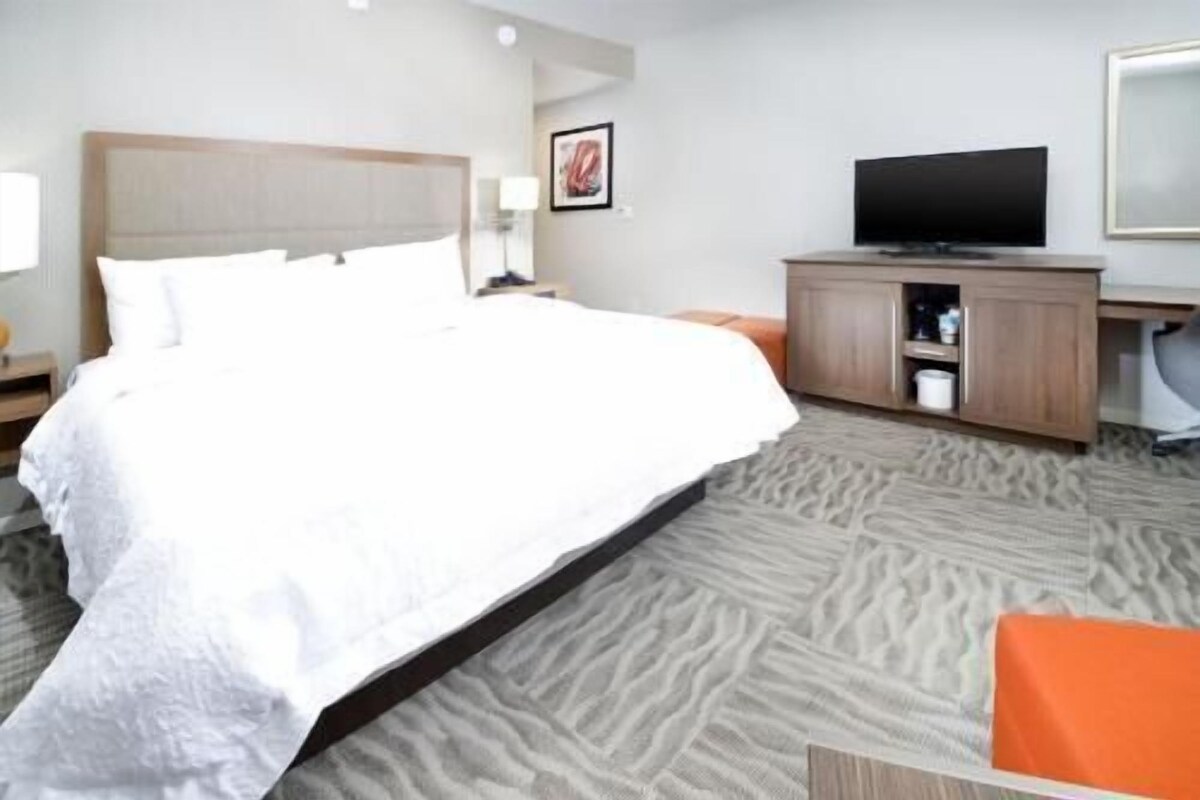 A hotel room with a bed, a television, a desk, and a chair.