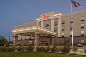A Hampton Inn hotel with a clear entrance, a flagpole with the American flag, and a parking area. - Hampton Inn Opelousas (Opelousas)