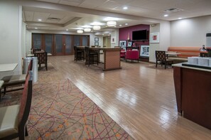 A hotel lobby with a reception desk, seating area, and a large screen TV. - Hampton Inn Opelousas (Opelousas)