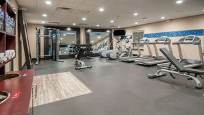 A gym with treadmills, elliptical machines, and a weightlifting area.