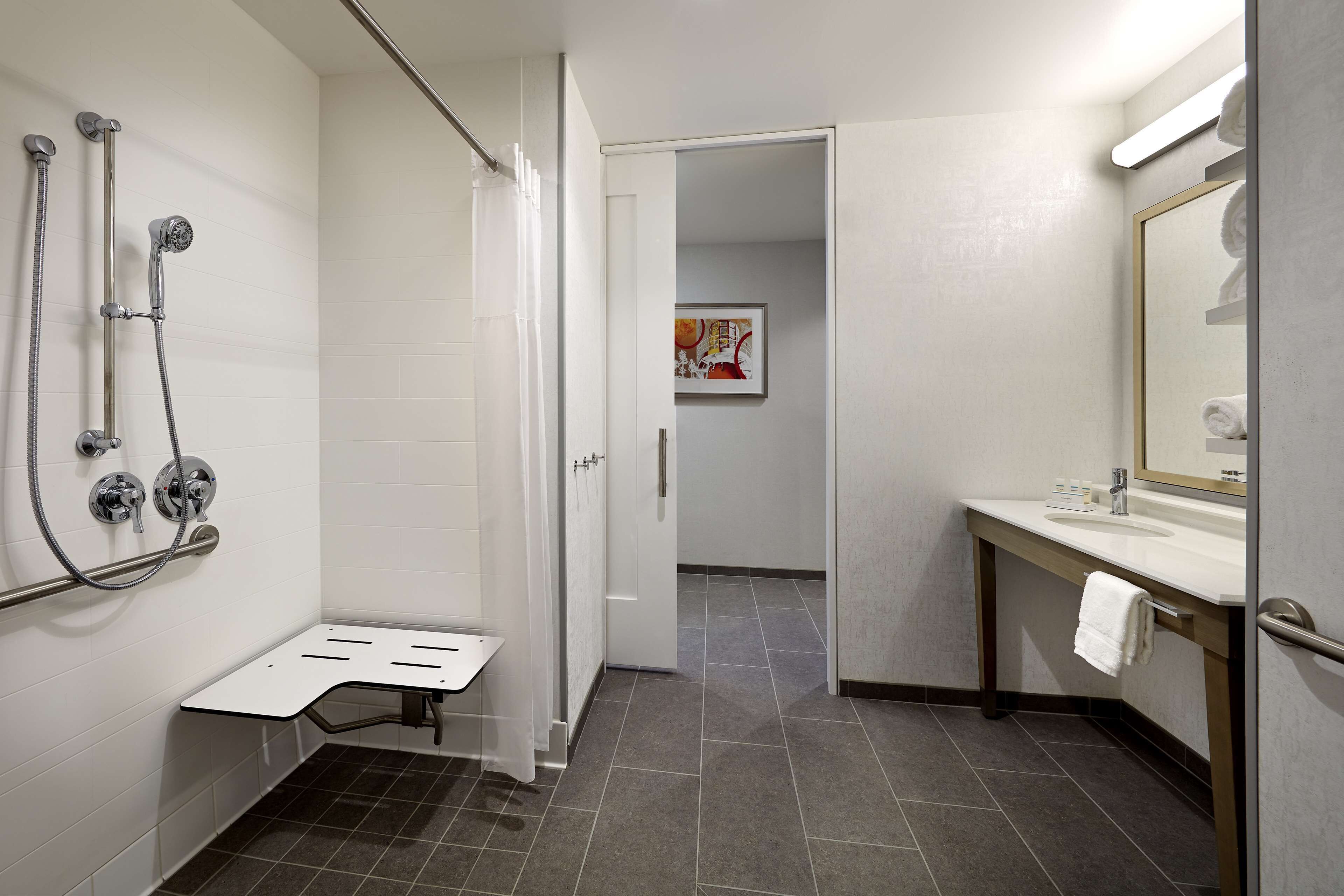 A modern bathroom with a shower, a sink, and a mirror.