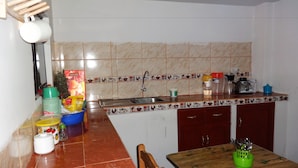 A kitchen with a tiled backsplash, a sink, a wooden table, and a chair. - Hostel Climbing Point (Independencia)