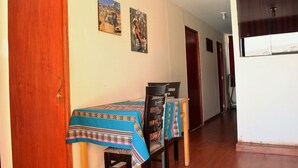 A dining area with a table covered by a patterned tablecloth, two chairs, and a wooden door. - Hostel Climbing Point (Independencia)