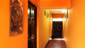 A narrow hallway with orange walls and a wooden door. - Hostel Climbing Point (Independencia)