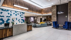 Um lobby moderno com balcão de recepção, área de estar e uma tela grande.