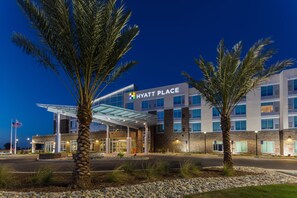 A modern Hyatt Place hotel with a glass entrance, palm trees, and a well-lit facade. - Hyatt Place Delano (Delano)