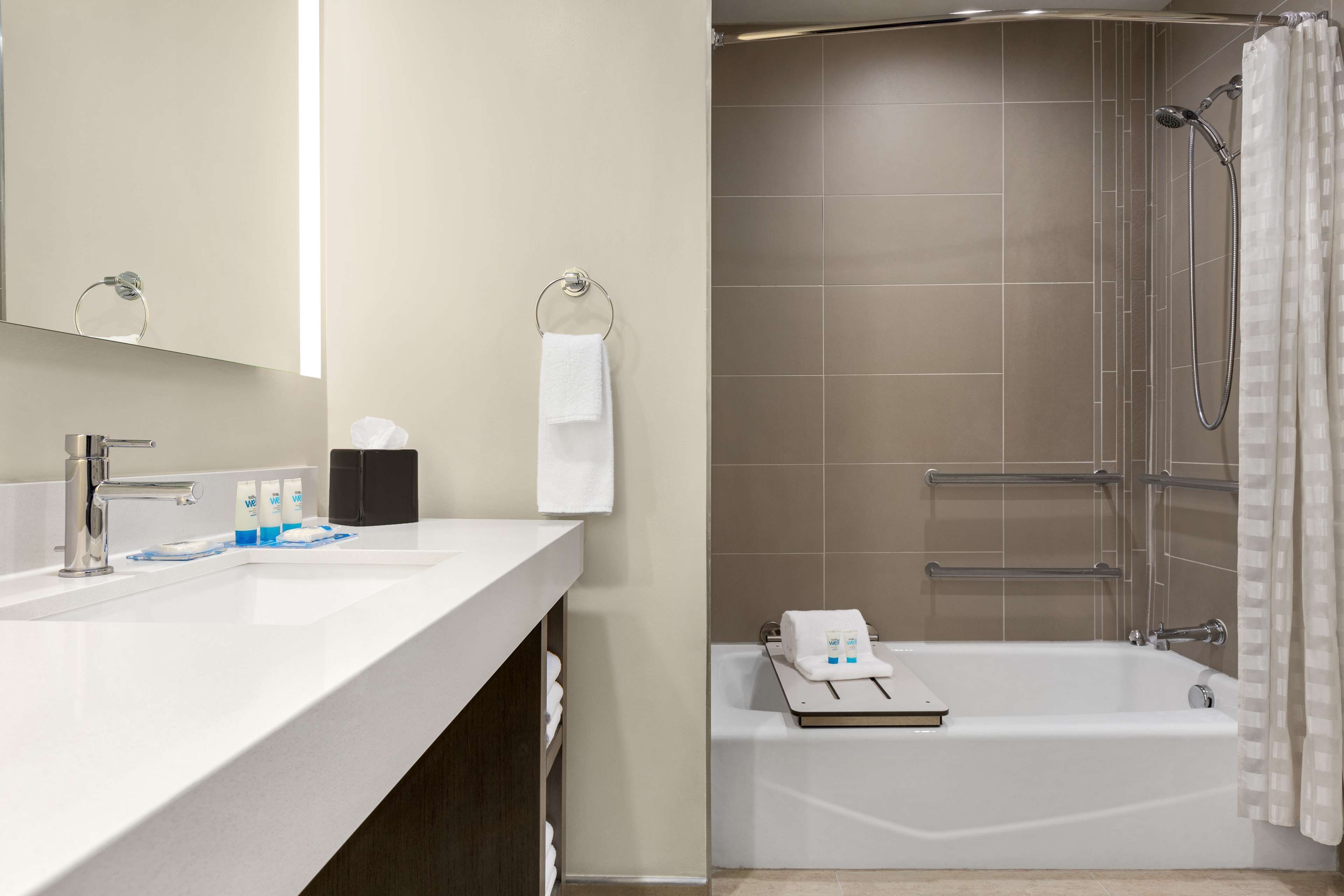 Ein modernes Badezimmer mit einem weißen Waschbecken, einem Spiegel, einer Dusche mit Glastür und einer Badewanne.