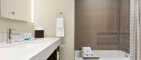 Ein modernes Badezimmer mit einem weißen Waschbecken, einem Spiegel, einer Dusche mit Glastür und einer Badewanne.