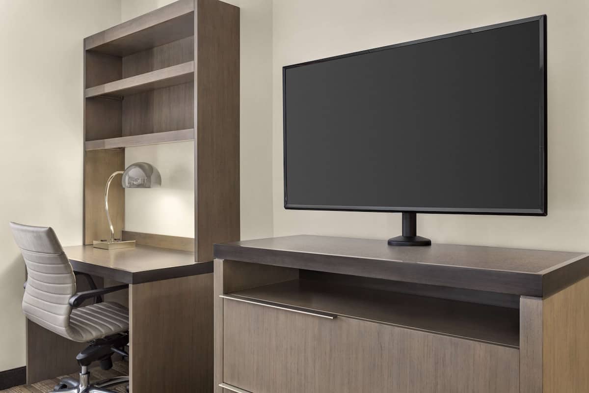 Un escriptori modern amb un monitor de pantalla plana, una cadira i prestatgeries integrades.