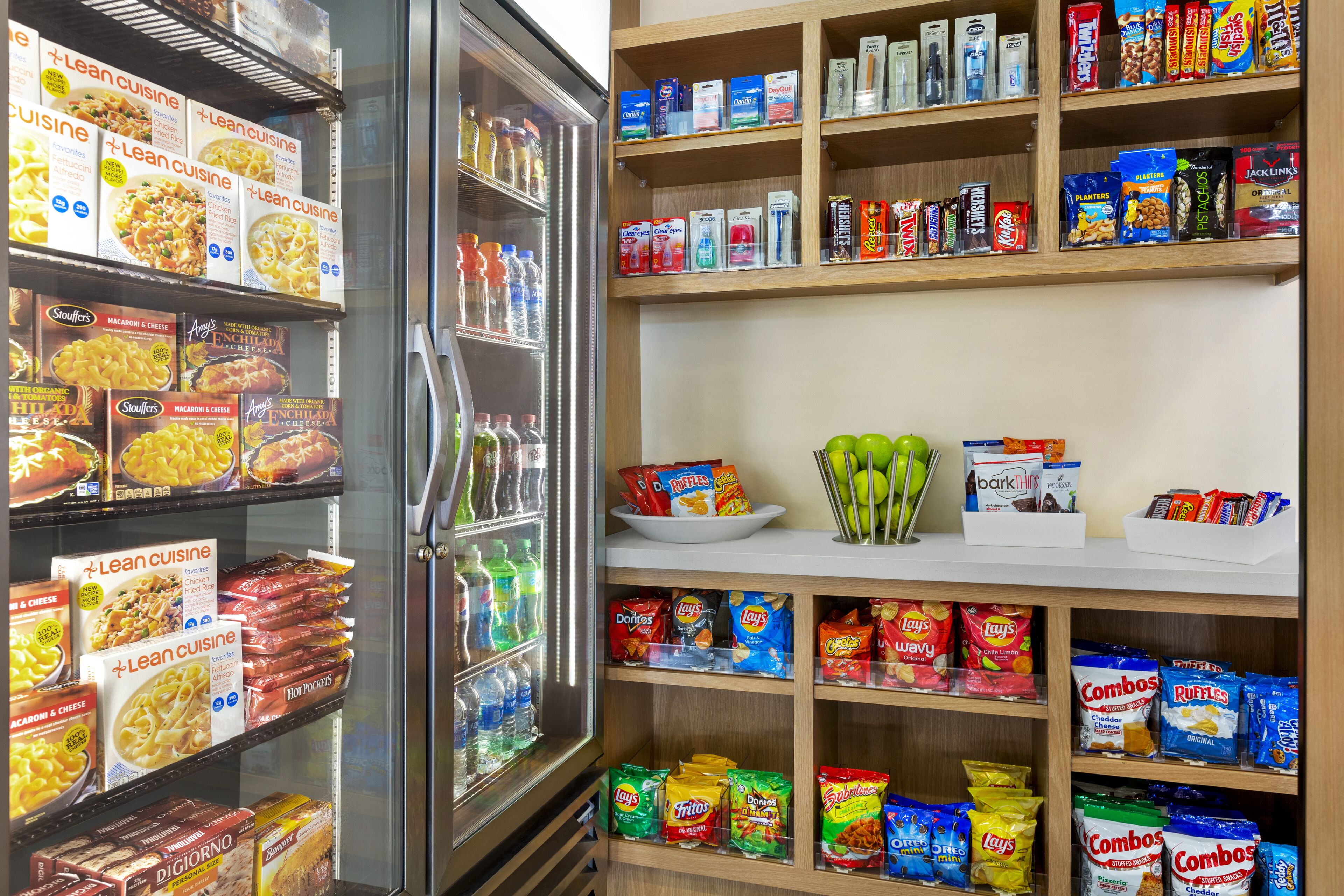 Un rayon réfrigéré proposant divers types de pâtes et de plats préparés, ainsi que des étagères adjacentes remplies d’en-cas, de boissons et d’autres produits alimentaires.